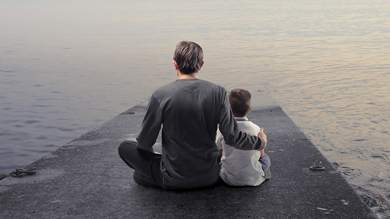 Father-and-son-sitting-on-a-wharf-and-observing-the-panorama